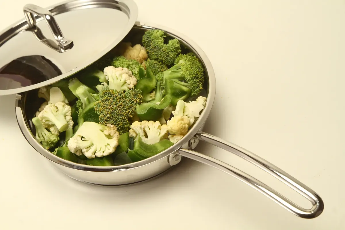 High-angle view of broccoli and cauliflower in a stainless steel pan, perfect for healthy cooking inspiration.