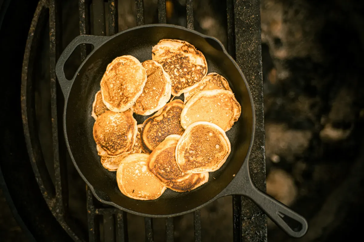 A delicious stack of golden pancakes cooked in a cast iron skillet, photographed from above.